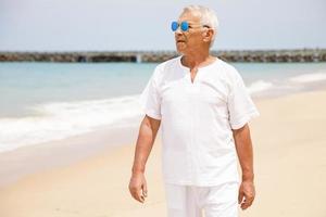 heureux homme âgé marchant sur la plage photo