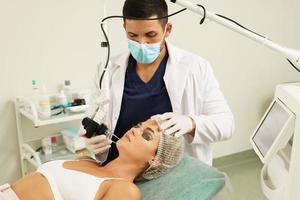 médecin dermatologue et cliente pendant le traitement de resurfaçage de la peau au laser photo
