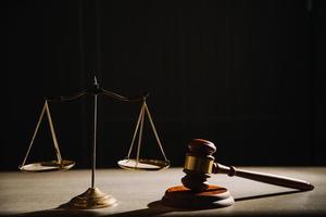 concept de justice et de droit. juge masculin dans une salle d'audience avec le marteau, travaillant avec, clavier d'ordinateur et d'accueil, lunettes, sur table à la lumière du matin photo