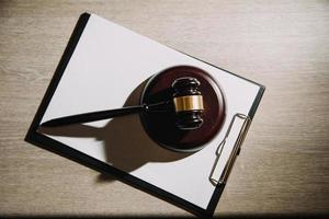 concept de justice et de droit. juge masculin dans une salle d'audience avec le marteau, travaillant avec, clavier d'ordinateur et d'accueil, lunettes, sur table à la lumière du matin photo