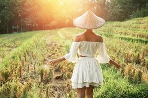 femme portant des vêtements naturels et un chapeau conique asiatique dans la rizière au coucher du soleil photo