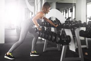 femme travaillant avec des haltères dans la salle de gym photo