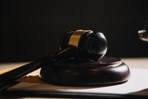 concept de justice et de droit. juge masculin dans une salle d'audience avec le marteau, travaillant avec, clavier d'ordinateur et d'accueil, lunettes, sur table à la lumière du matin photo