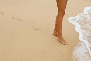 jambes féminines et empreintes de pas sur le sable photo