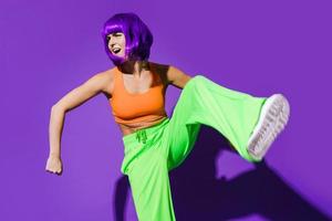 danseuse insouciante portant des vêtements de sport colorés s'amusant sur fond violet photo