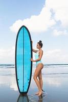 jeune femme portant un maillot de bain rayé avec planche de surf sur la plage photo