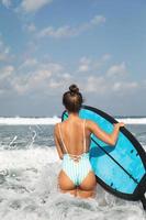 jeune femme portant un maillot de bain rayé avec planche de surf sur la plage photo