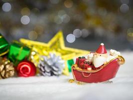 joyeux père noël avec une boîte de cadeaux sur le traîneau à neige l'arrière-plan est un décor de noël.le père noël et un décor de noël sur la neige. concept de joyeux noël et bonne année photo