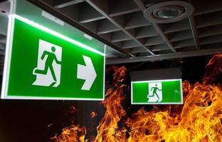 un feu de flamme chaude et un panneau d'évacuation d'incendie vert sont suspendus au plafond du bureau la nuit. le concept de formation à l'évacuation en cas d'incendie et de préparation à l'évacuation photo