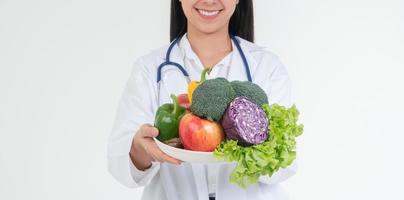 médecin ou nutritionniste tenant des fruits frais orange, pommes rouges et vertes et sourire en clinique. concept de régime alimentaire sain d'aliments nutritifs comme ordonnance pour une bonne santé, les fruits sont des médicaments photo