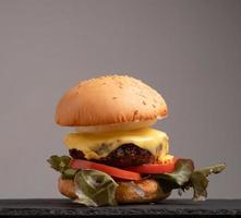 hamburger fait maison frais et savoureux avec légumes frais, laitue, tomate, fromage sur une planche à découper. espace libre pour le texte photo