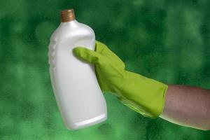 main avec gant de protection tenant l'emballage des produits de nettoyage utilisés pour l'hygiène domestique