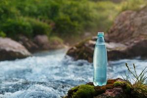 bouteille en plastique avec de l'eau potable fraîche sur le fond d'un ruisseau de montagne, à l'état sauvage. eau fraîche photo
