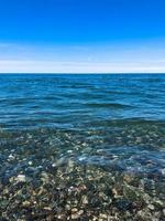 belles pierres rondes multicolores sur la mer, les rivières, les lacs, l'étang, l'océan et l'eau bouillante avec des vagues sur la plage rocheuse d'une station balnéaire tropicale à l'horizon et au ciel. vue verticale photo