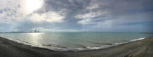 belles pierres rondes multicolores sur la mer, les rivières, les lacs, l'étang, l'océan et l'eau bouillante avec des vagues sur la plage rocheuse d'une station balnéaire tropicale à l'horizon et au ciel. panorama photo