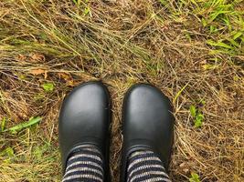 des vêtements confortables et élégants pour le forestier. des galoches en caoutchouc noir sont portées aux pieds dans des chaussettes de laine chaudes. isolation contre le froid. temps humide d'automne. vêtements pour marcher sur l'herbe mouillée photo