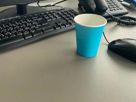 espace de travail féminin de style minimal. bureau moderne avec clavier d'ordinateur, tasse à café, verres, cahier, enveloppe, carte papier vierge sur fond blanc. mise à plat, vue de dessus photo