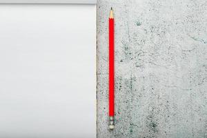 bloc-notes avec un crayon rouge sur fond clair pour l'écriture. espace vide libre pour écrire sur une feuille vierge d'un cahier. photo