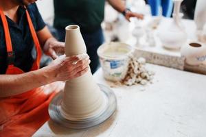 mains de jeune potier, a été réalisé sur gamme des mains d'un potier habilement confectionnant un pot d'argile blanche. photo