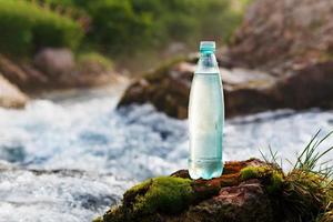 bouteille en plastique avec de l'eau potable fraîche sur le fond d'un ruisseau de montagne, à l'état sauvage. eau fraîche photo