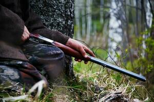 gros plan de fusil de chasse entre les mains d'un chasseur assis à l'affût. en attente de jeu photo