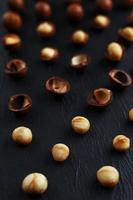 purifiée et la coquille répète les noix de macadamia sur fond de pierre texturée noire. concept d'alimentation saine photo