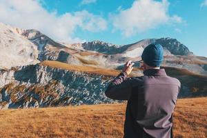 un voyageur touristique photographie des montagnes couvertes de nuages sur un smartphone photo