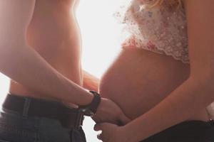 heureux jeune couple femme enceinte et mari aimant mari. une femme attend un bébé avec un gros ventre. père touche et prend soin d'une mère enceinte photo