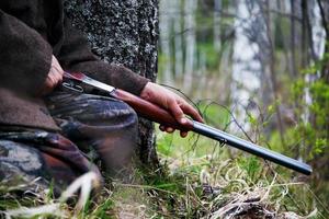 gros plan de fusil de chasse entre les mains d'un chasseur assis à l'affût. en attente de jeu photo