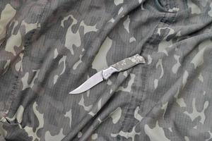 couteau militaire sur les vêtements de camouflage de l'armée se bouchent. arrière-plan avec espace de copie pour la conception de services militaires ou spéciaux photo