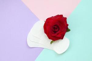 tampons menstruels avec fleur de rose rouge se trouve sur la vue de dessus de fond multicolore photo