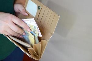 mains féminines tenant des billets de hryvnia ukrainienne dans une petite pochette ou un portefeuille photo