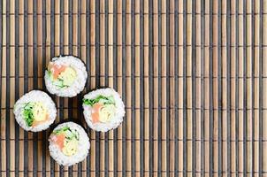 les rouleaux de sushi reposent sur un tapis de couture en paille de bambou. cuisine asiatique traditionnelle. vue de dessus. minimalisme à plat tourné avec espace de copie photo