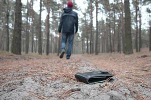 jeune homme perd son sac à main avec des billets en euros sur le chemin du bois de sapin d'automne russe. insouciance et perte de concept de portefeuille photo