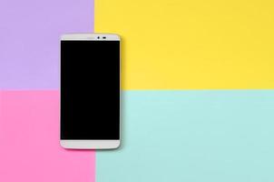 smartphone moderne avec écran noir sur fond de texture de papier de couleurs bleu pastel, jaune, violet et rose de mode dans un concept minimal photo