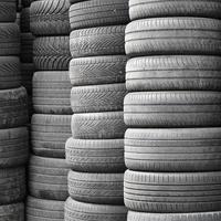 Vieux pneus usagés empilés avec des pieux élevés dans le garage de l'atelier de pièces de voiture secondaire photo