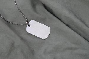 Perles militaires argentées avec dog tag sur uniforme de fatigue vert foncé photo