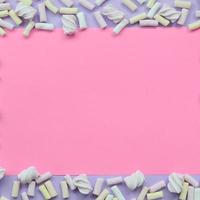 guimauve colorée disposée sur fond de papier violet et rose. cadre texturé créatif pastel. minimal photo