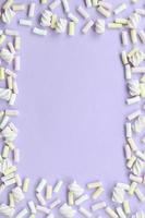 guimauve colorée disposée sur fond de papier violet. cadre texturé créatif pastel. minimal photo
