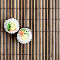 les rouleaux de sushi reposent sur un tapis de couture en paille de bambou. cuisine asiatique traditionnelle. vue de dessus. minimalisme à plat tourné avec espace de copie photo