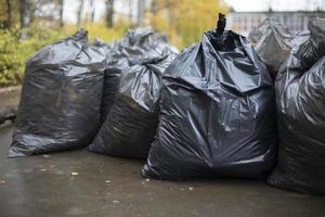 sacs poubelles noirs. de nombreux paquets noirs. nettoyage dans la cour. photo