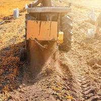 récolte dans le village, récolte des pommes de terre avec un tracteur avec une charrue et un crible vibrant. photo