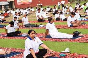 new delhi, inde, 21 juin 2022 - séance d'exercices de yoga en groupe pour les personnes du complexe sportif de yamuna à delhi lors de la journée internationale du yoga, grand groupe d'adultes assistant à un cours de yoga au stade de cricket photo