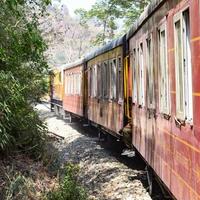 petit train se déplaçant sur les pentes de la montagne, belle vue, un côté montagne, un côté vallée se déplaçant sur le chemin de fer jusqu'à la colline, parmi la forêt naturelle verdoyante. train jouet de kalka à shimla en inde, train indien photo