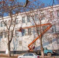 dnepropetrovsk, ukraine - 02.09.2022 constructeur dans un panier de grue répare le revêtement d'une structure métallique sur le mur de la façade d'un bâtiment. photo