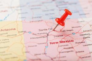 aiguille de bureau rouge sur une carte des états-unis, du nouveau mexique et de la capitale de santa fe. gros plan du nouveau mexique avec tack rouge photo