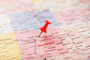 aiguille de bureau rouge sur une carte des états-unis, du nouveau mexique et de la capitale de santa fe. gros plan du nouveau mexique avec tack rouge photo