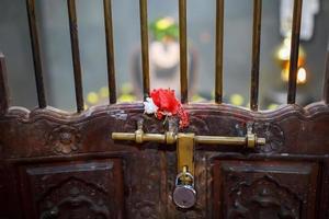 verrouiller l'ancienne porte du temple indien avec un treillis et un boulon. fleur rouge sur le réseau photo
