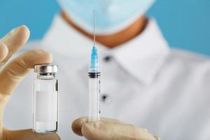 un médecin en gants de caoutchouc tient une ampoule avec un vaccin et une seringue, gros plan. photo
