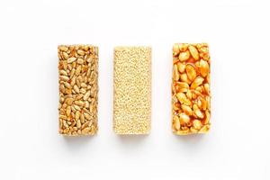 barre de céréales granola avec cacahuètes, sésame et graines d'affilée sur fond blanc. vue de dessus trois barres assorties, isoler photo